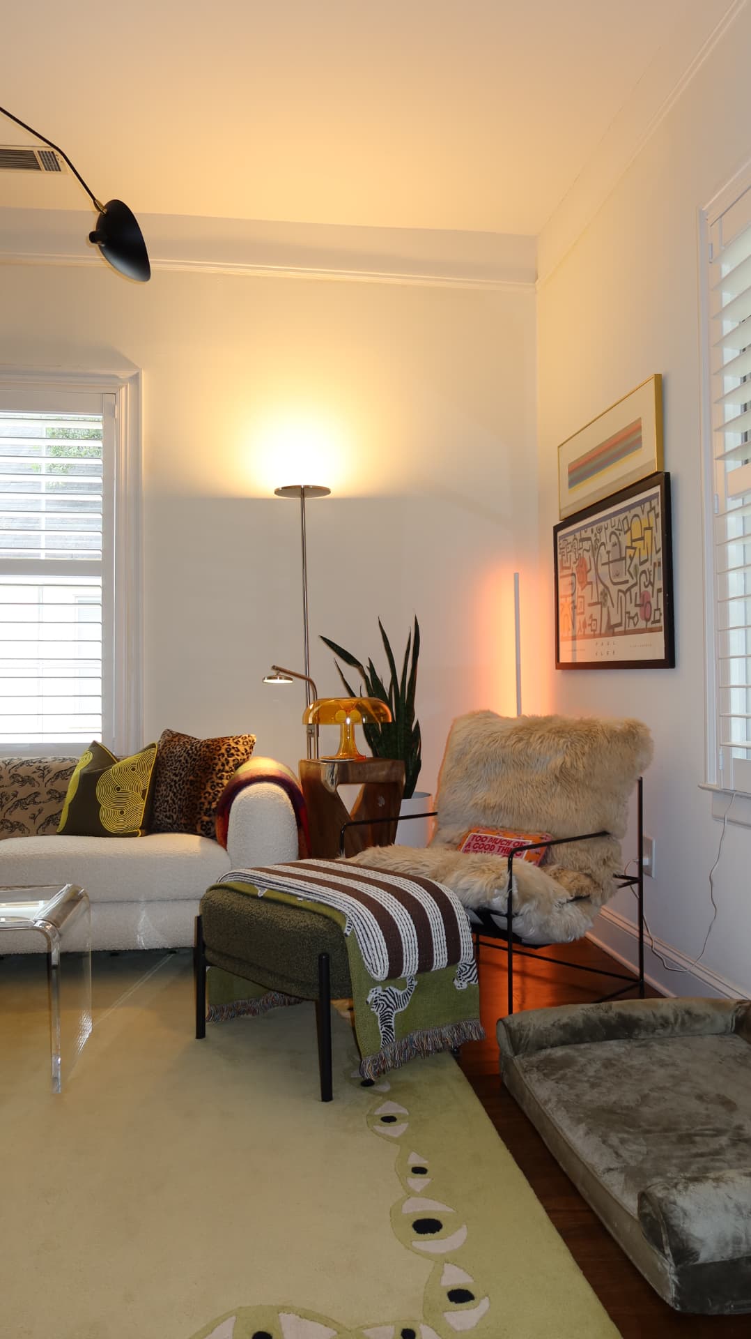 Bright living room with cream sofa, colorful pillows, shearling chair, and modern art